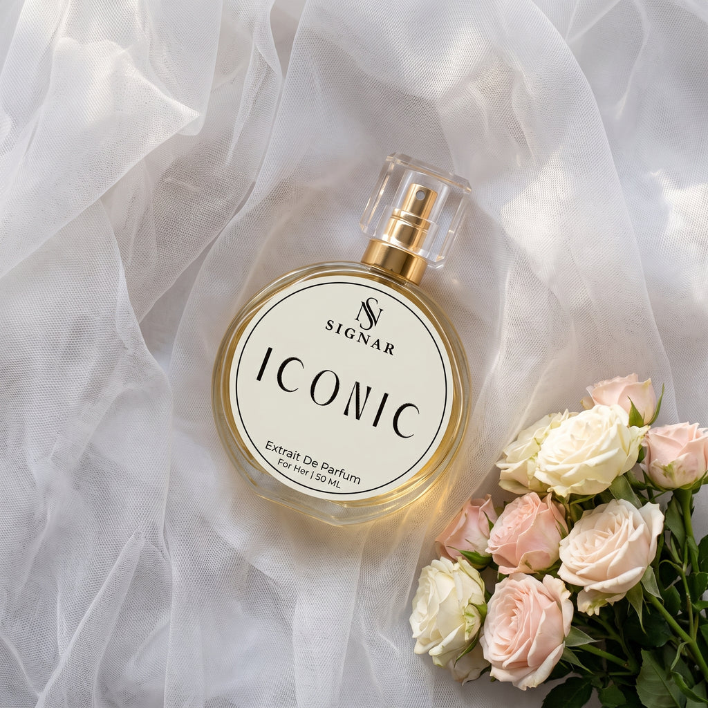 SIGNAR ICONIC Extrait De Parfum perfume bottle with a gold cap, styled on white tulle fabric next to pink and white roses.
