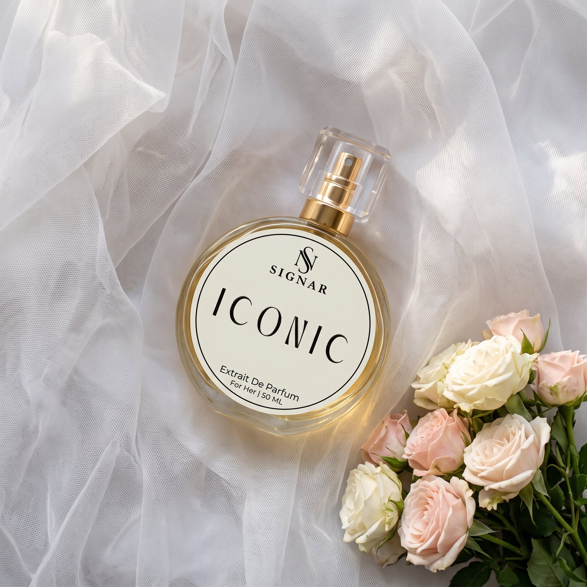SIGNAR ICONIC Extrait De Parfum perfume bottle with a gold cap, styled on white tulle fabric next to pink and white roses.