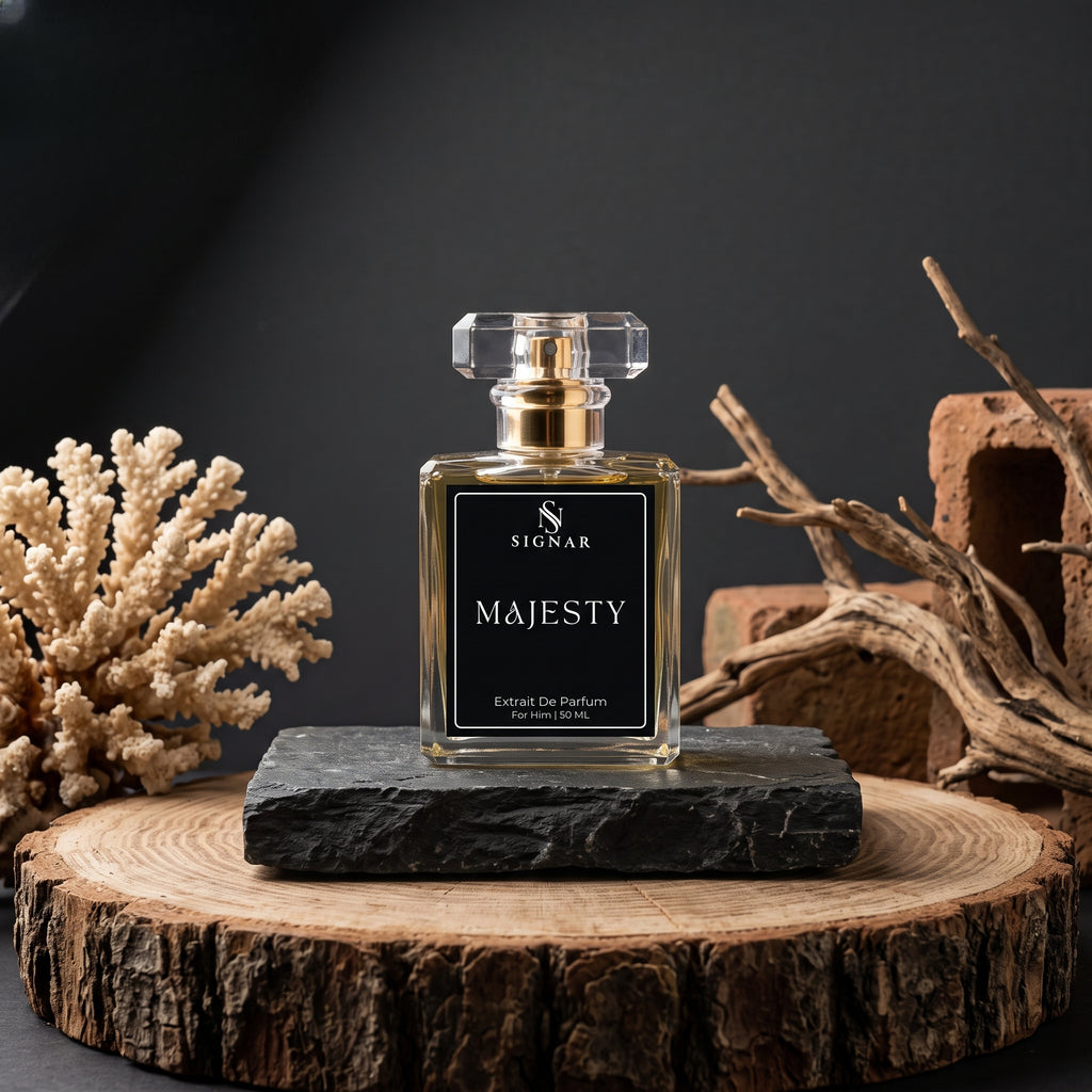 SIGNAR MAJESTY Extrait De Parfum Turmeric (60ml) perfume bottle, displayed on a dark slate block atop a rustic wood slice. The bottle is surrounded by natural props including dried branches and a coral branch against a dark background.