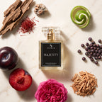 A rectangular glass perfume bottle labeled SIGNAR MAJESTY sits on a light marble surface, surrounded by fragrance-inspired ingredients including a sliced plum, a pink rose, a green citrus spiral, blueberries, wood chips, saffron threads, and a small stone.