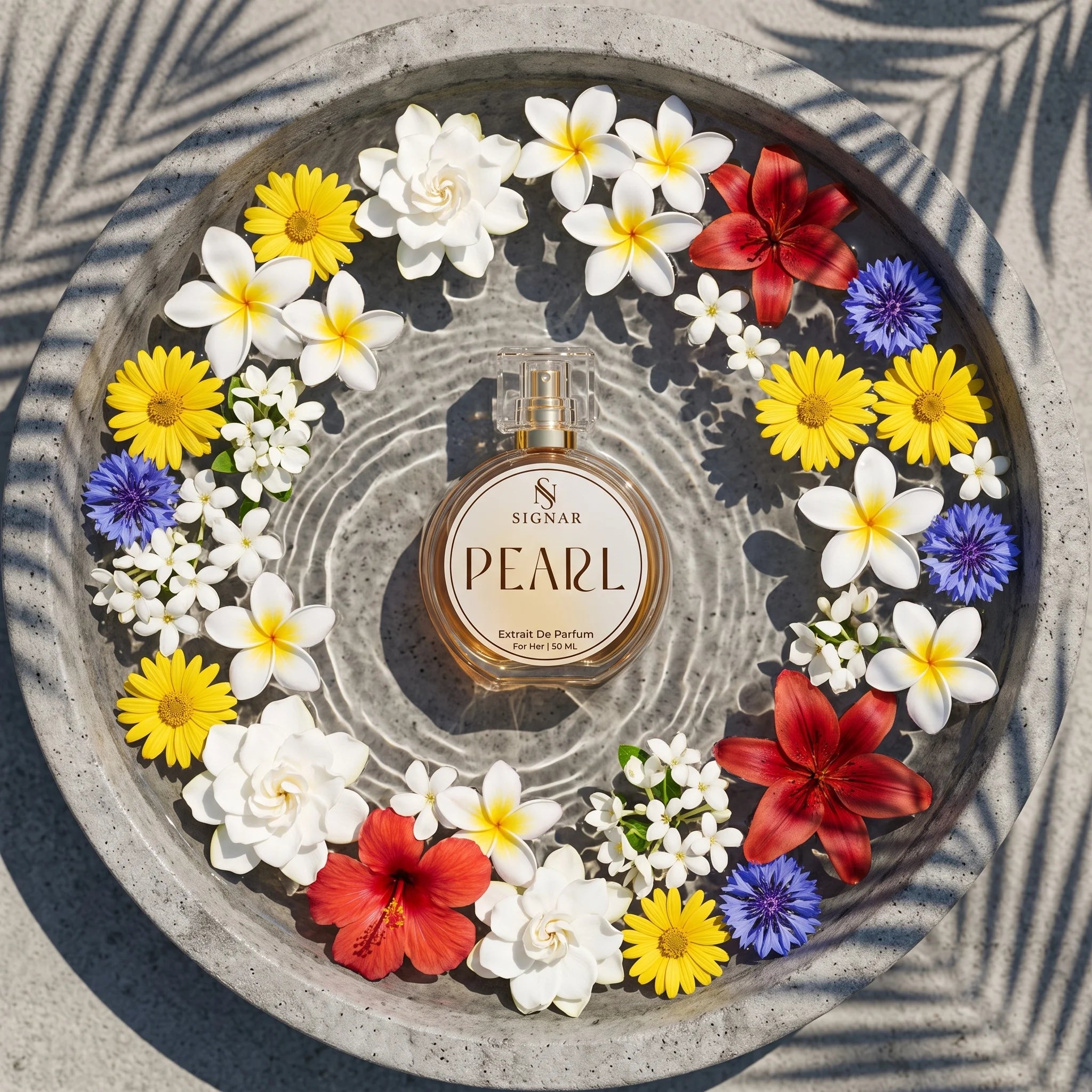 A round glass perfume bottle labeled 'SIGNAR PEARL' sits centered in a circular concrete tray filled with white, yellow, red, and purple flowers. The scene is photographed from above on a stone surface with leaf shadows cast across it.