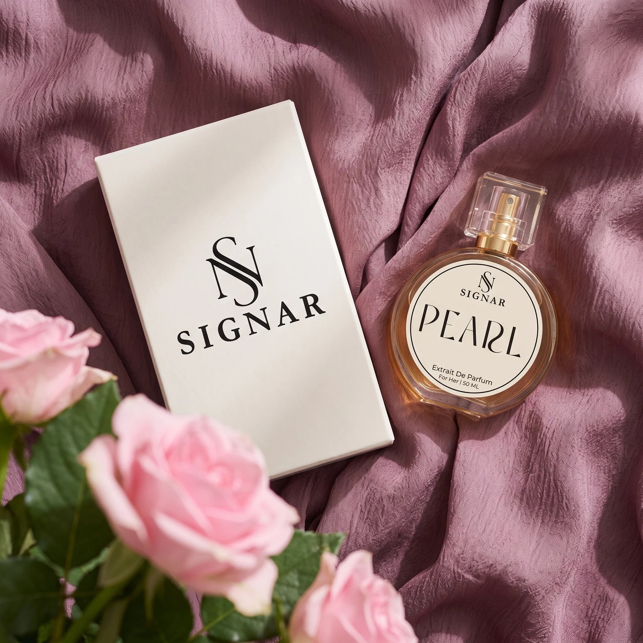 SIGNAR Pearl Extrait de Parfum perfume bottle next to its white box, styled on a draped dusty purple fabric with pink roses in the foreground.